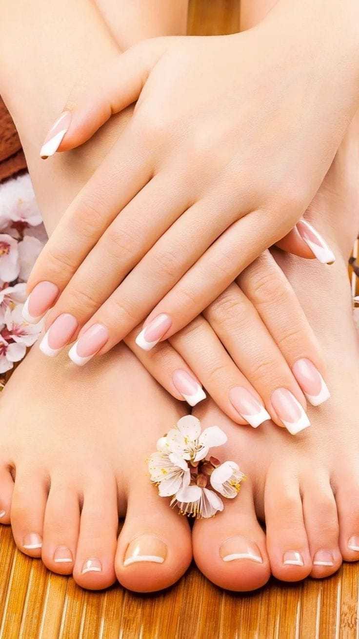 Hands and feet with manicured nails adorned with small white flowers.